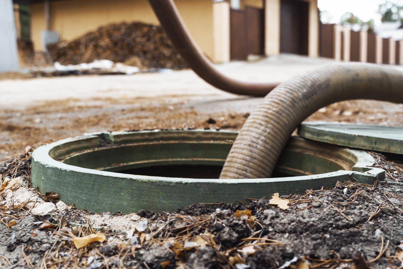 A septic pumping hose in an open tank at a house