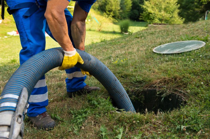 A technician pumping a septic tank through an open lid